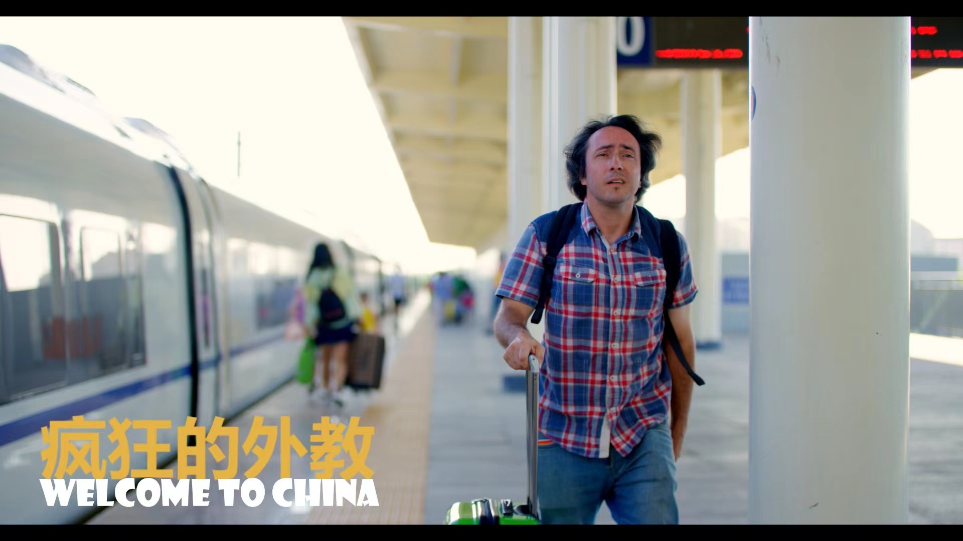 The main character stands with his suitcase on a railway station platform in China.